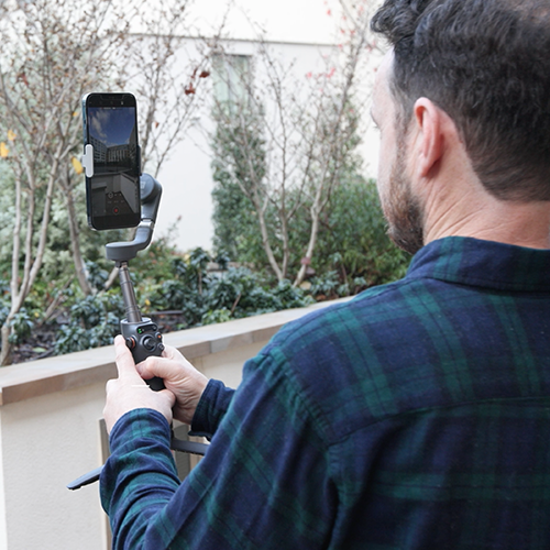 An image of a real estate agent filming a property video outside a development.